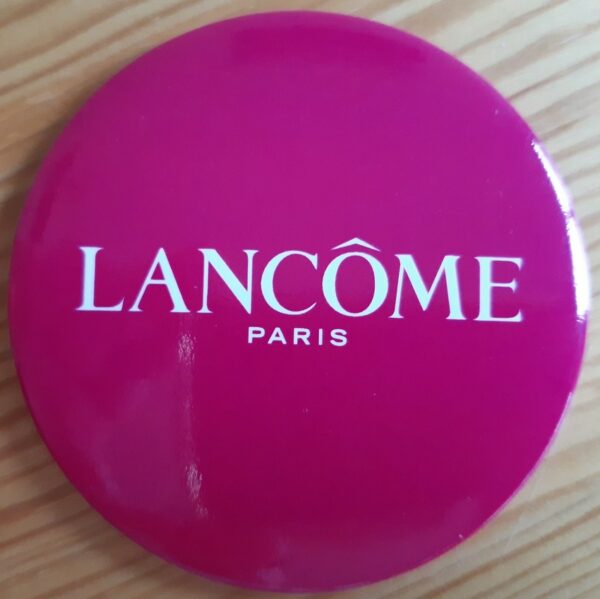 "Lancôme Paris" Miroir rond, fond rouge, écrit central en blanc sous film plastique.